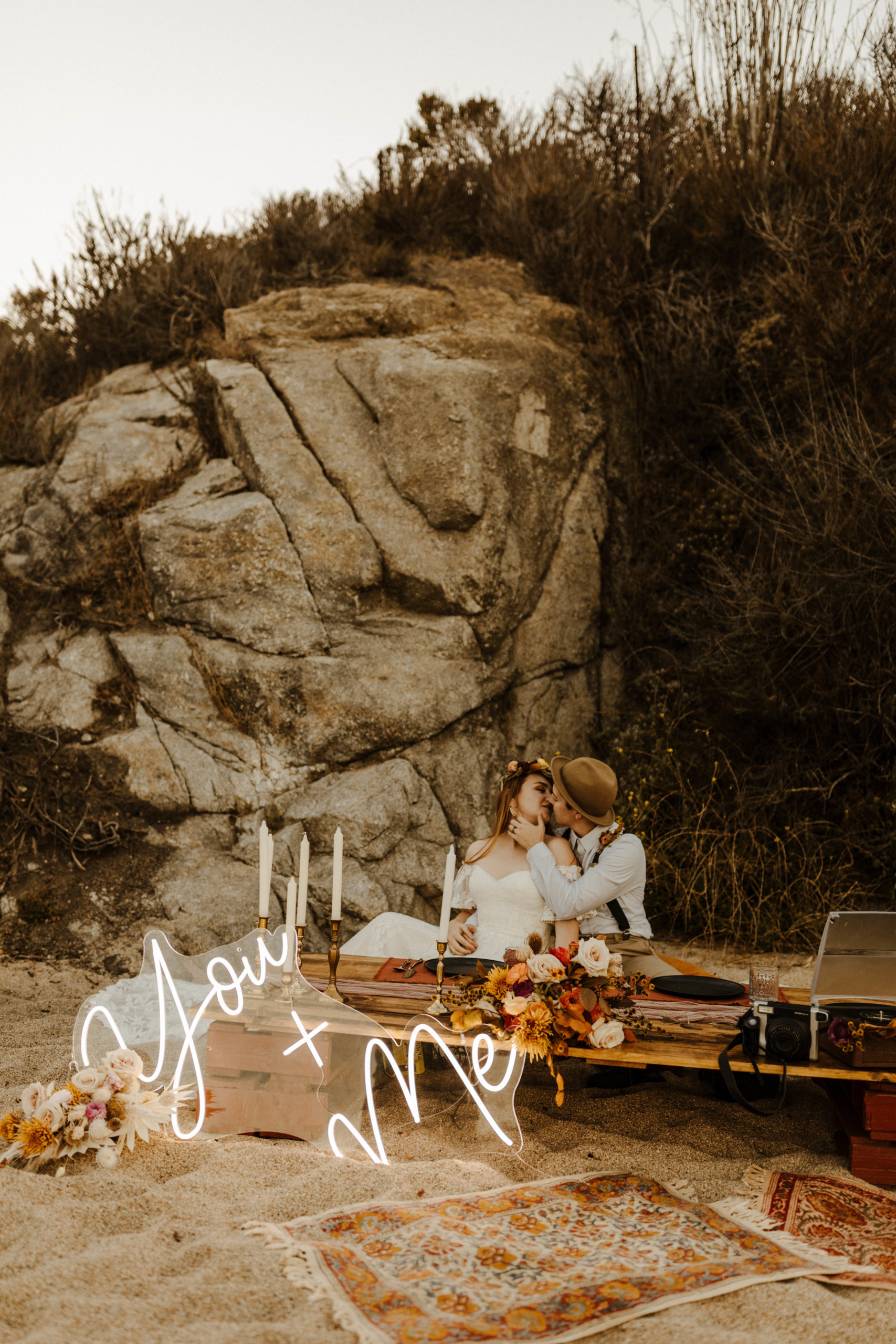 Same Sex Female couple at head table in big sur elopement with boho details and a "you and me" neon sign